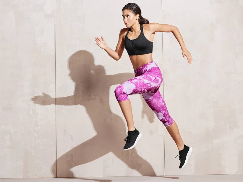 Žena beží v športovej podprsenke a legínach s potlačou.