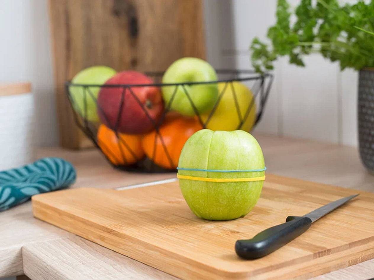 Jablko pripevnené gumičkami na drevenej doske.