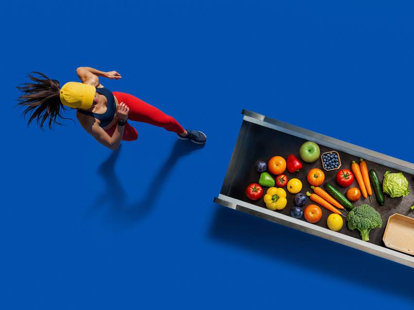 Žena beží smerom k prepravke plnej čerstvého ovocia a zeleniny.